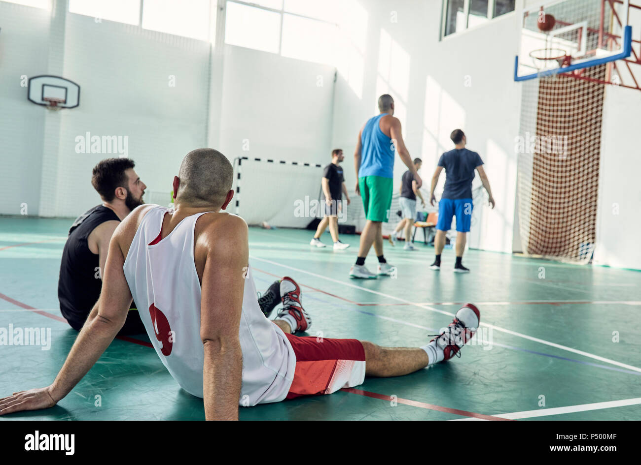 Basketball players during break, sitting on court Stock Photo