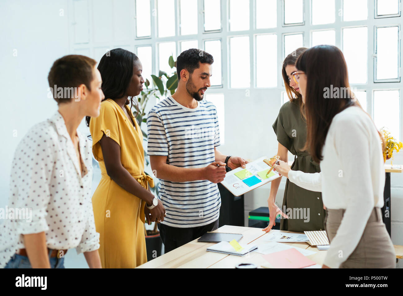 Colleagues working together at desk in office discussing papers Stock Photo