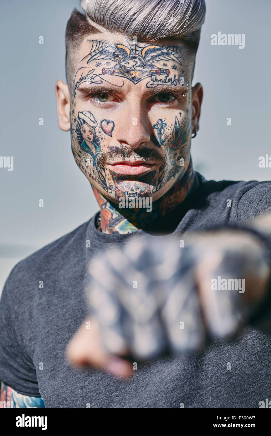Portrait of tattooed young man outdoors clenching his fist Stock Photo