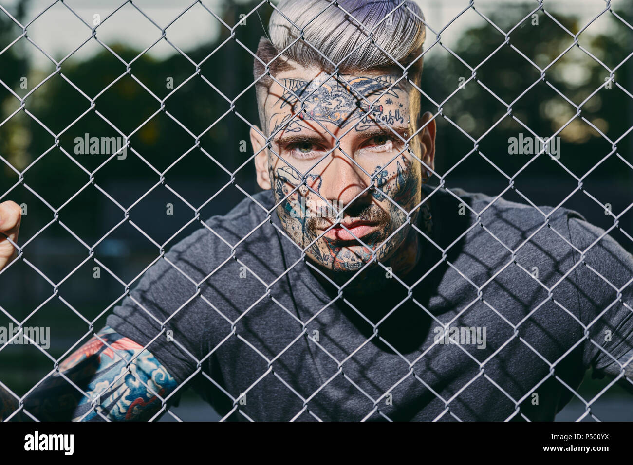 Portrait of tattooed young man behind fence Stock Photo