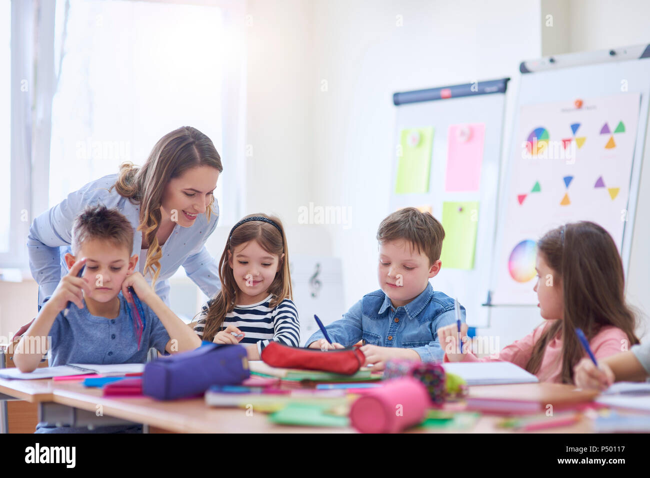 Smiling teacher helping pupils with their tasks in class Stock Photo