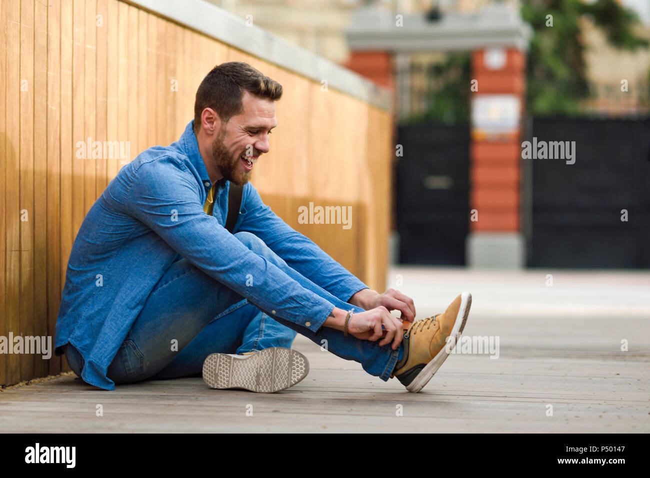 Young man laughing, sitting on footbridge Stock Photo