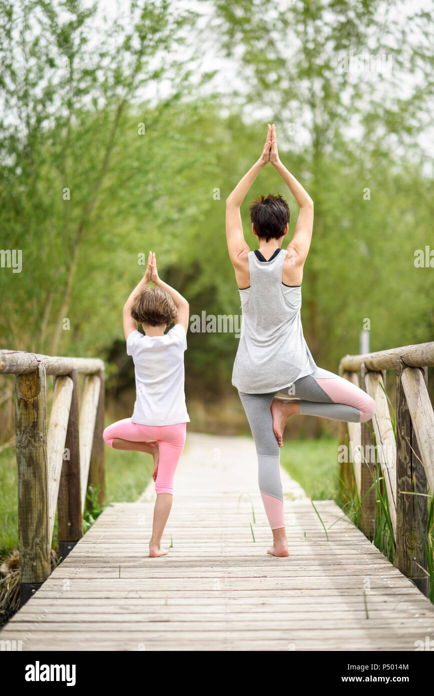 Rear view of mother and daughter doing yoga on boardwalk Stock Photo