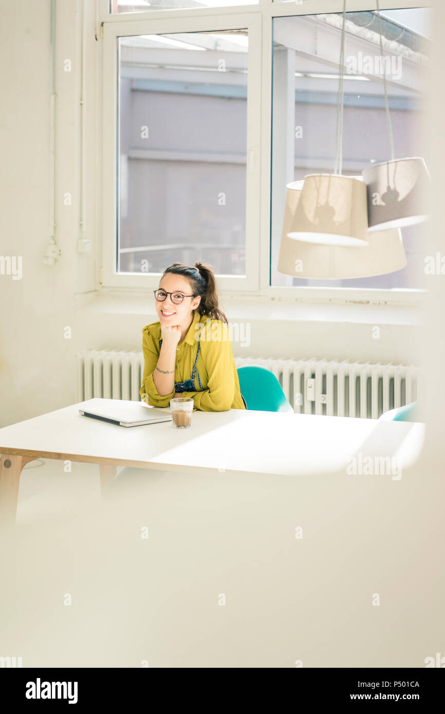 Portrait of happy freelancer sitting at desk in studio Stock Photo