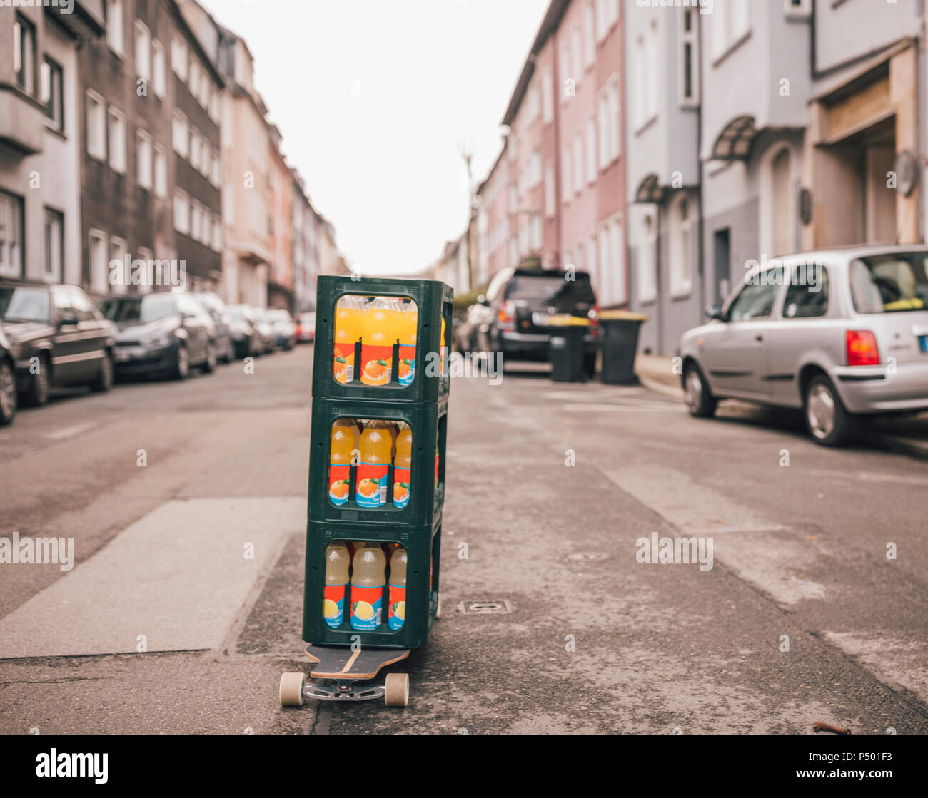 Stack of three boxes with lemonade bottles standing on longboard on the street Stock Photo