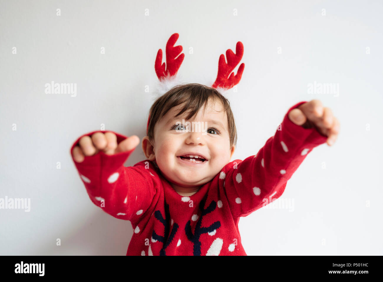 Portrait of happy baby girl with reindeer antlers headband at Christmas time Stock Photo
