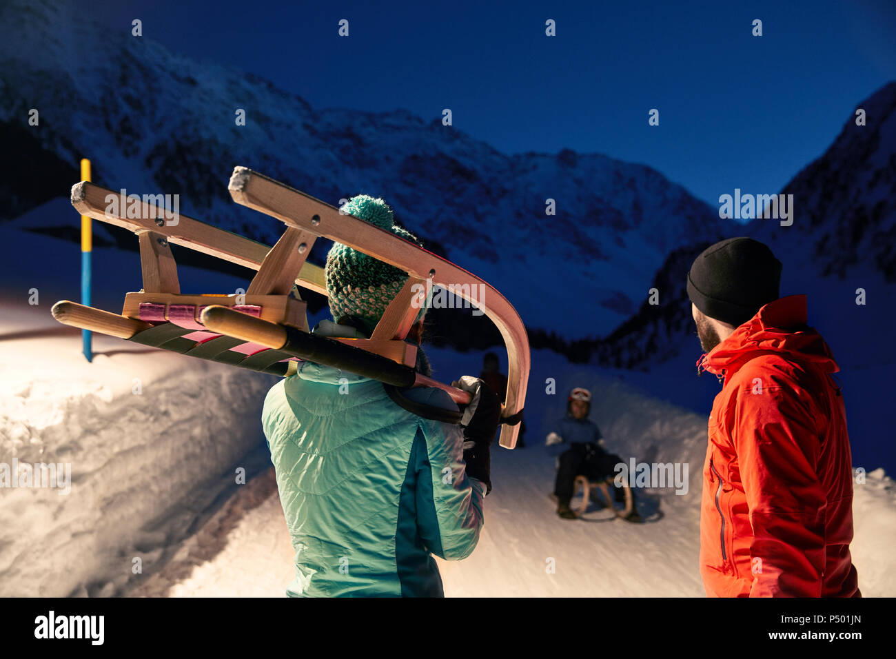 Couple with sledge in snow-covered landscape at night Stock Photo