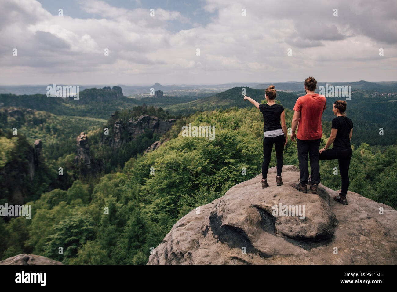 Germany, Saxony, Elbe Sandstone Mountains, friends on a hiking trip standing on rock Stock Photo