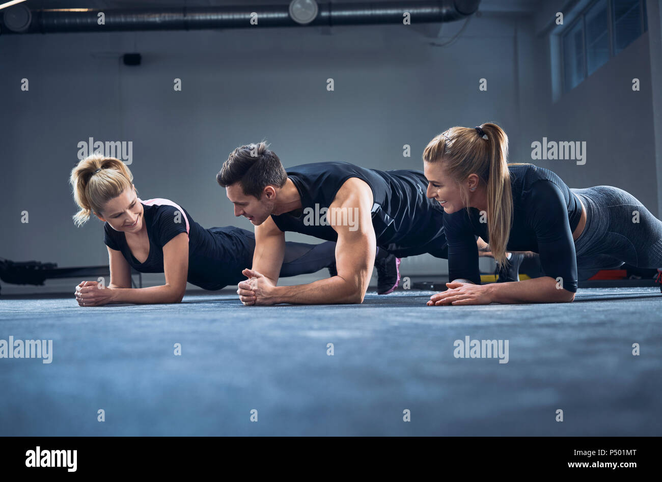 Three people doing plank exercise at gym Stock Photo