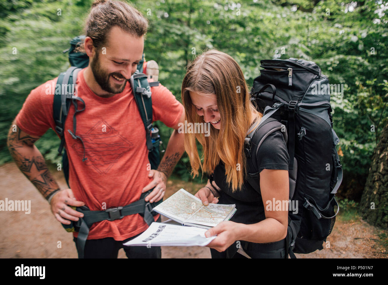 Happy young couple on a hiking trip reading map Stock Photo