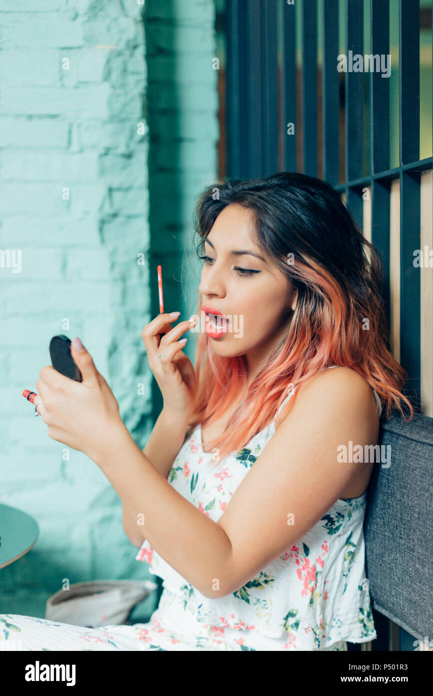 Portrait of young woman applying lip gloss Stock Photo