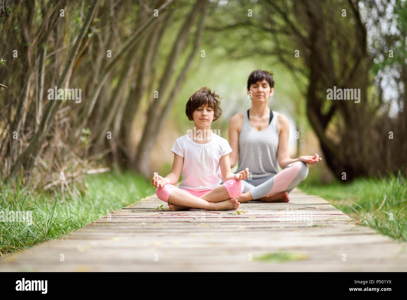Mother and daughter doing yoga on boardwalk Stock Photo