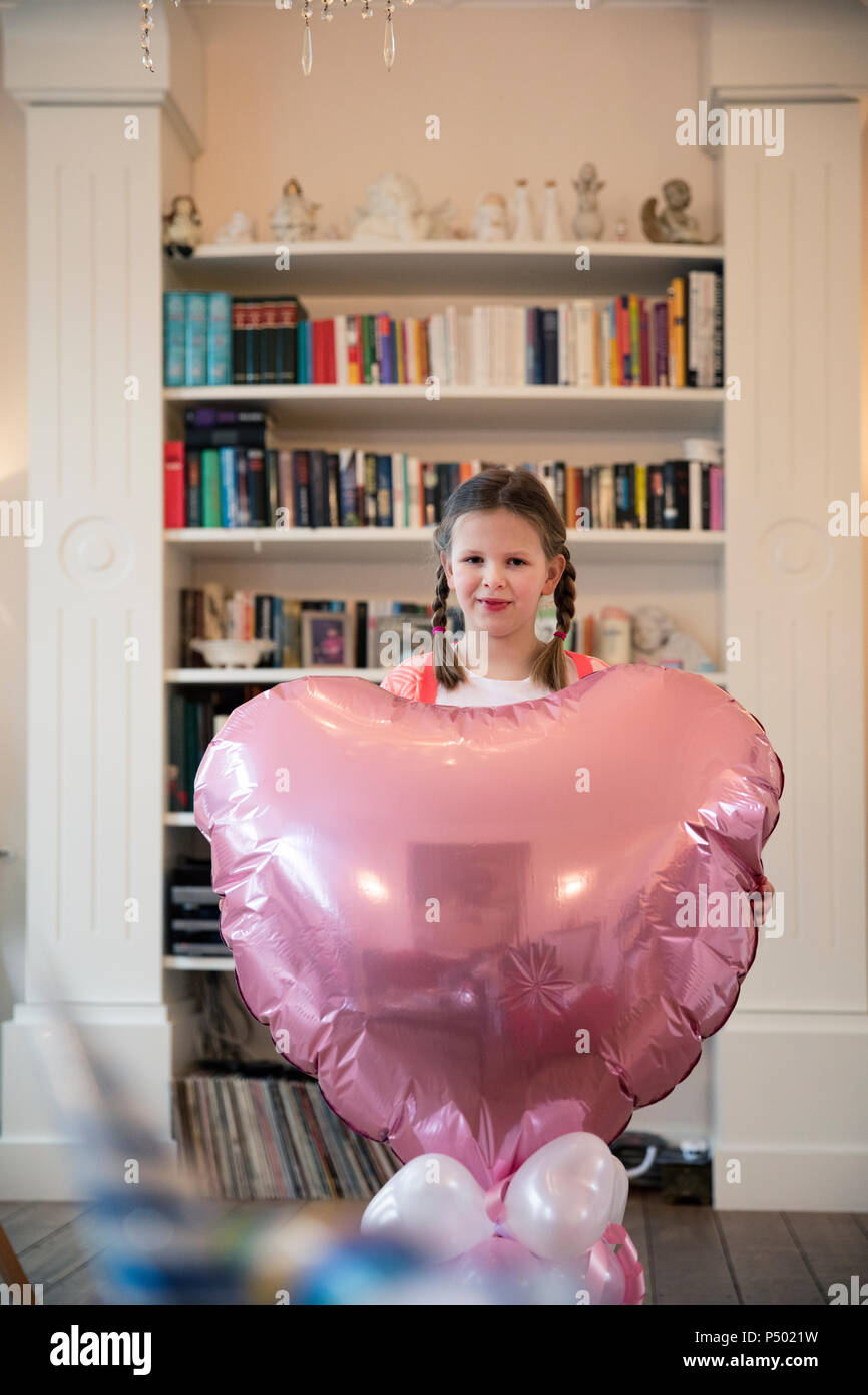 Portrait of girl with braids holding big heart-shaped balloon Stock Photo