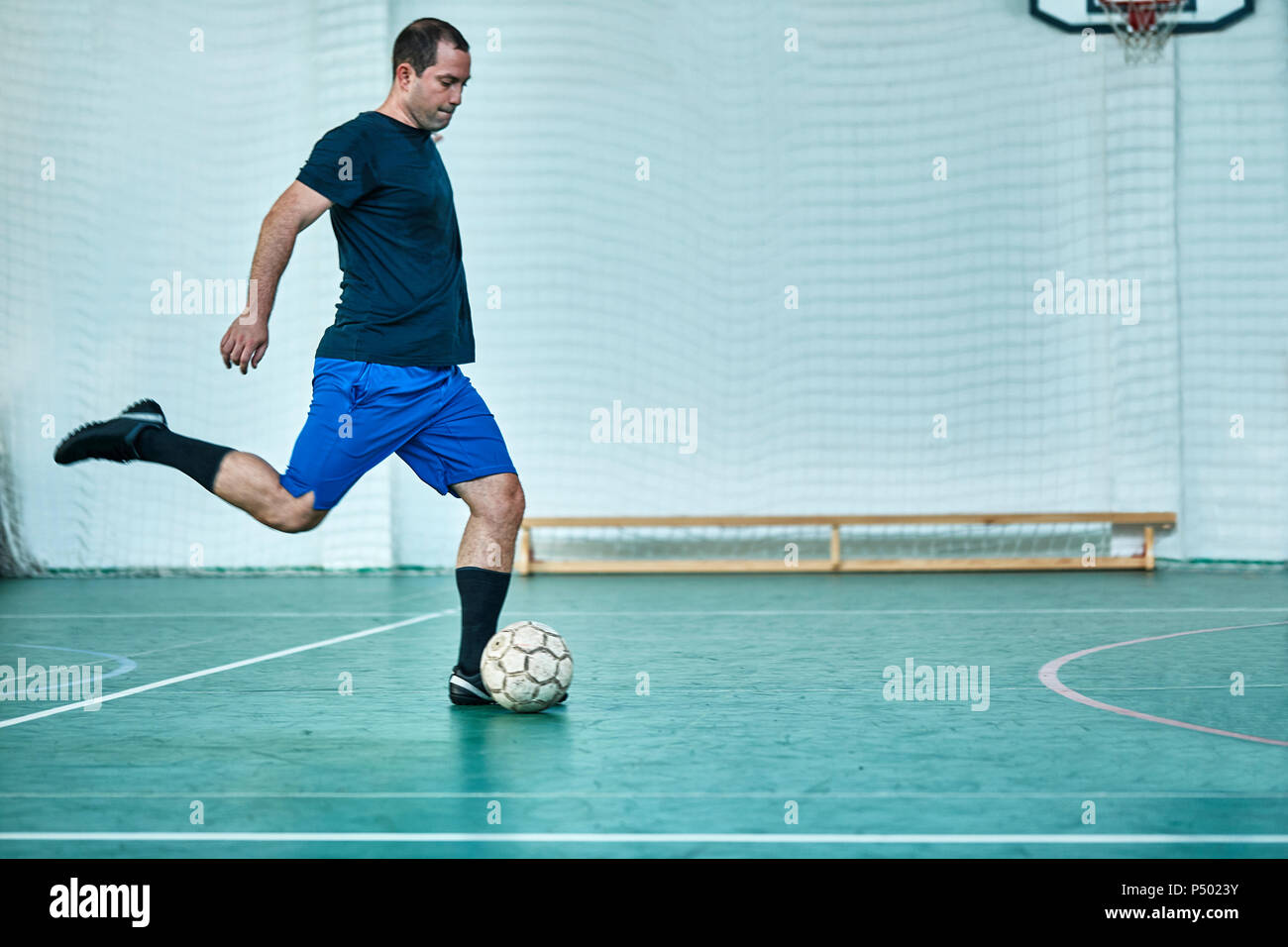 Man playing indoor soccer shooting the ball Stock Photo