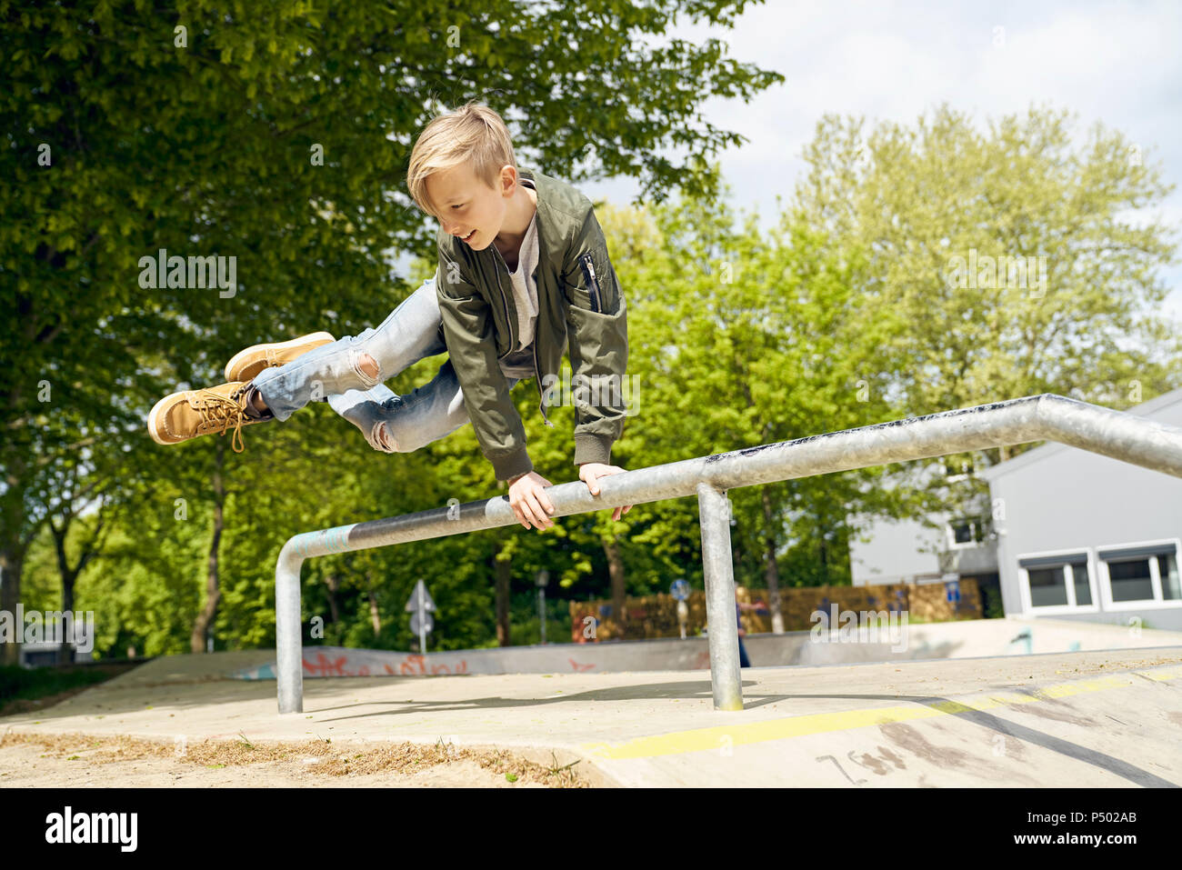 Boy jumping over railing in skatepark Stock Photo Alamy