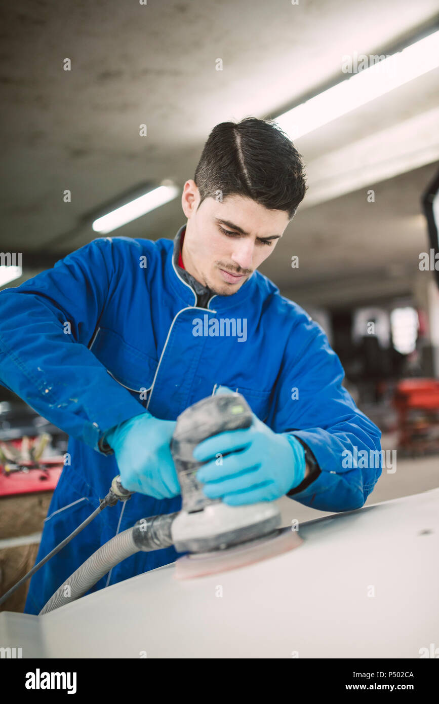 Man polishing the hood of a car in a workshop Stock Photo