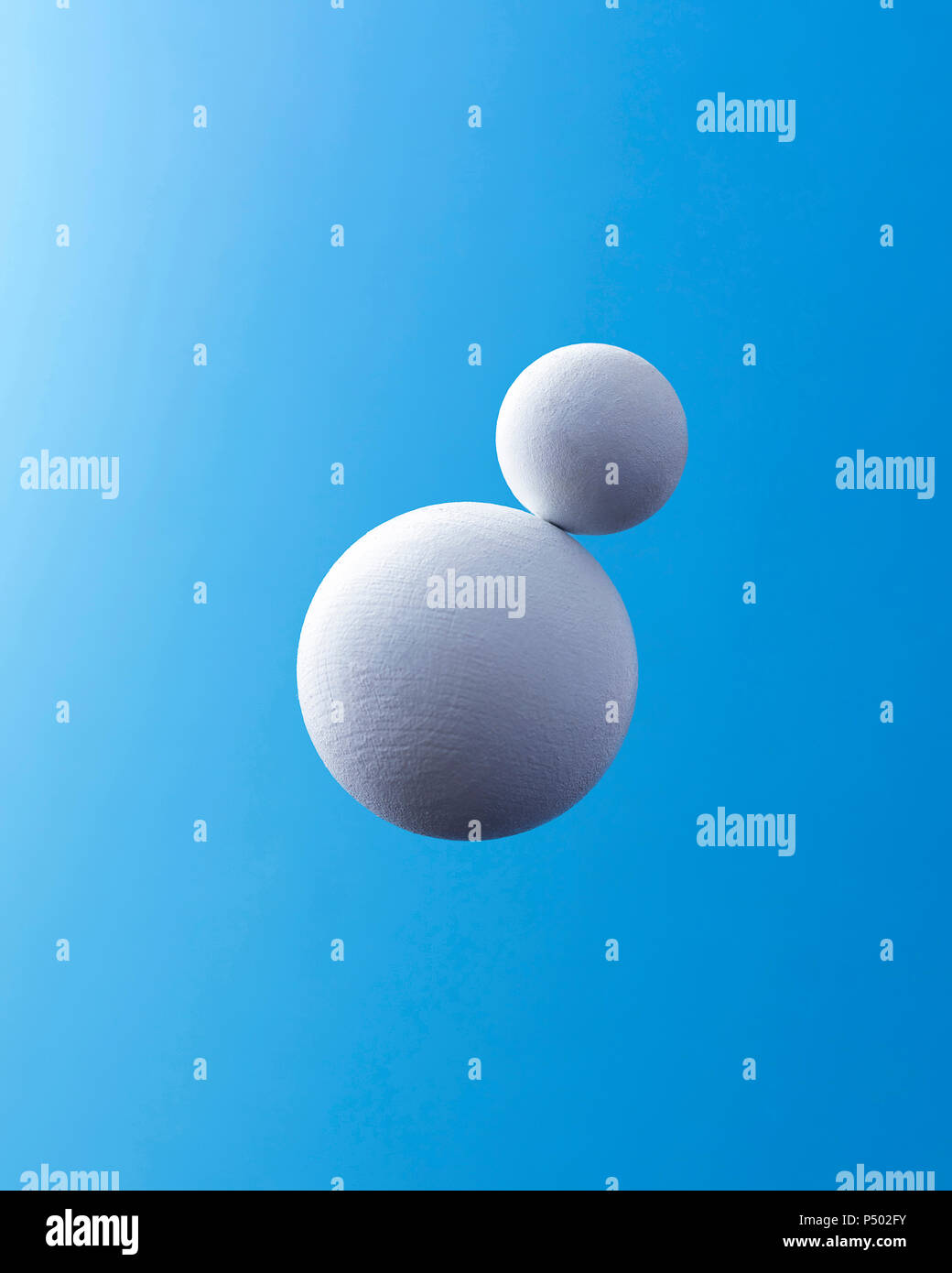 Two white spheres in front of blue background Stock Photo