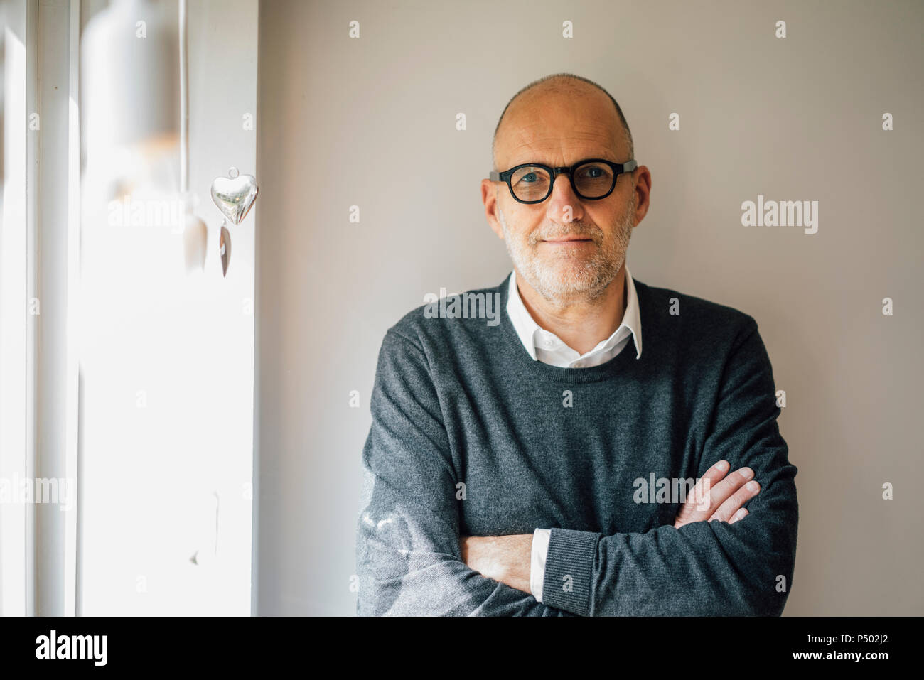 Portrait of a senior man, staning in front of wall with arms crossed Stock Photo