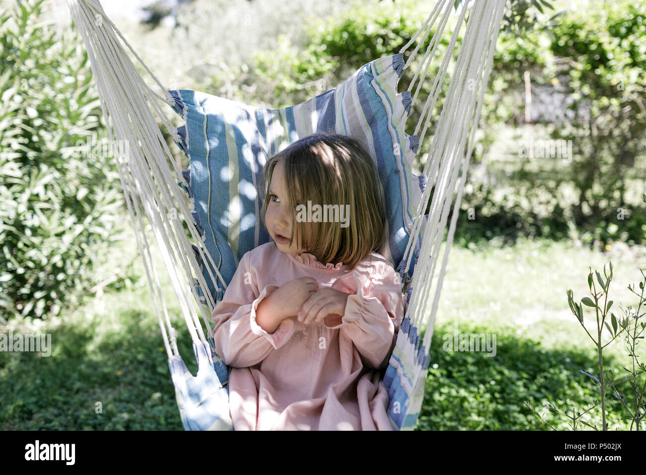 Little girl sitting on hammock in the garden Stock Photo