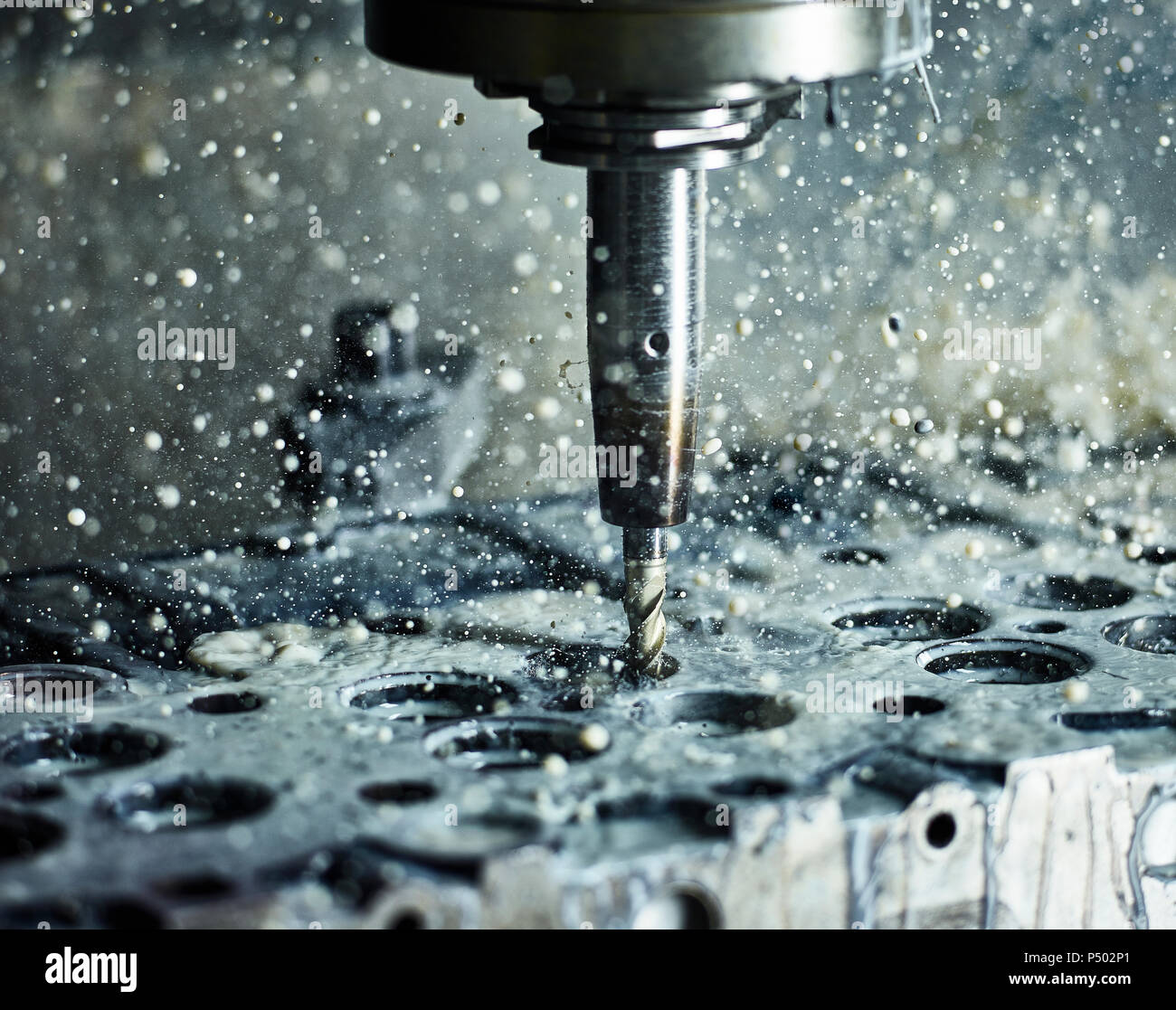 CNC machine drilling into cylinder head with coolant Stock Photo