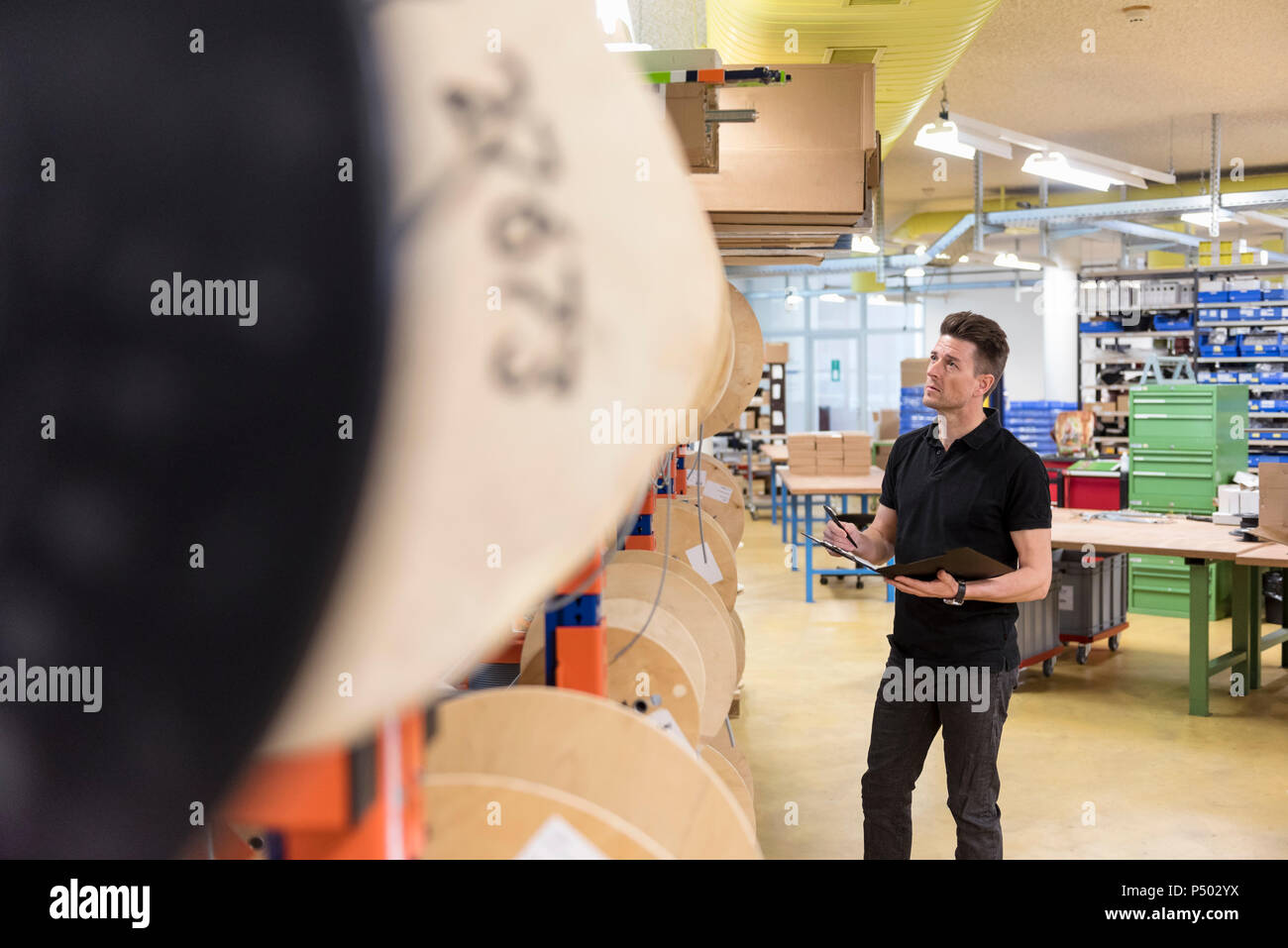 Man with clipboard in factory taking notes Stock Photo