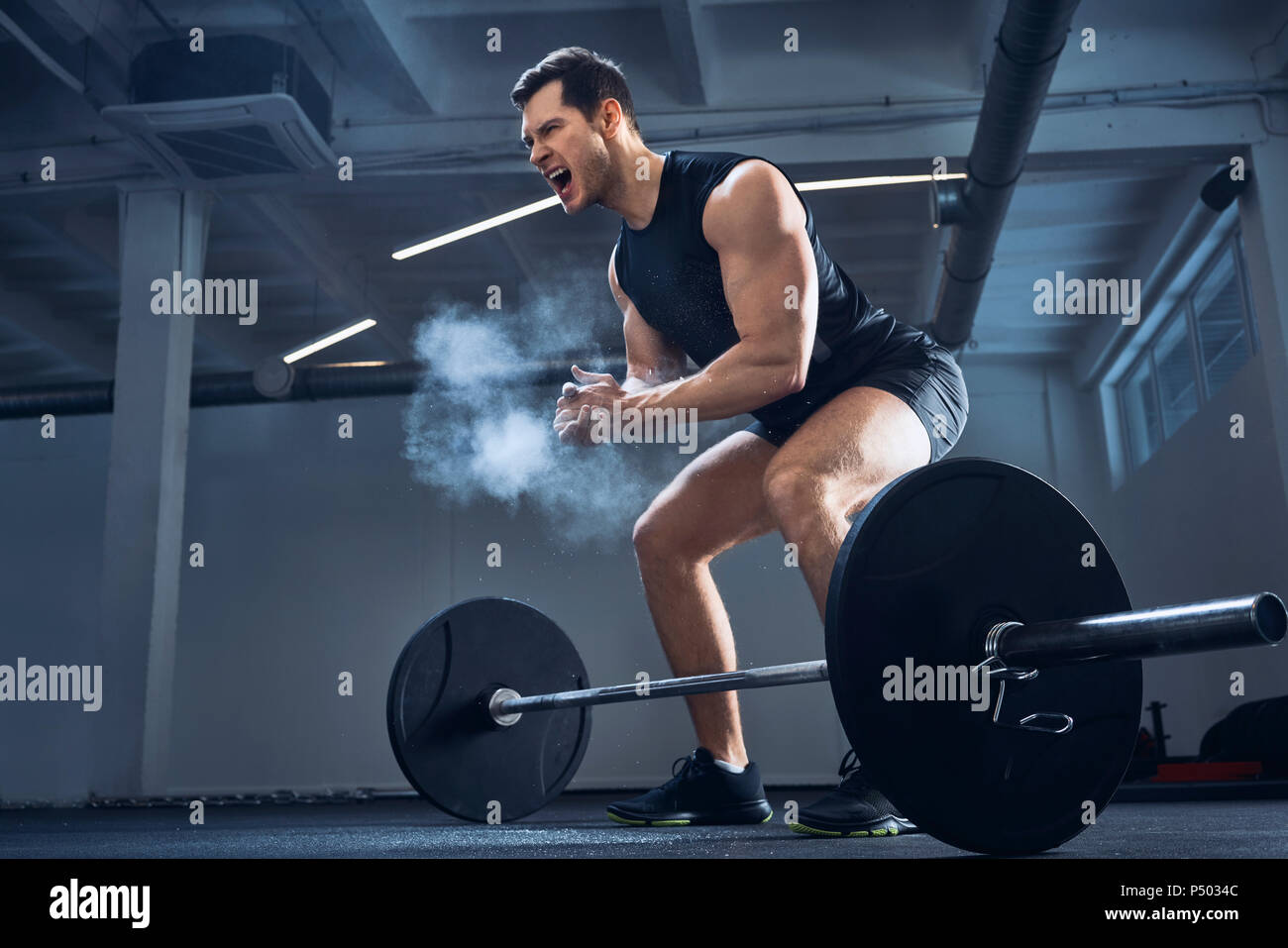 Motivated weightlifter clapping hands before barbell workout at gym Stock Photo