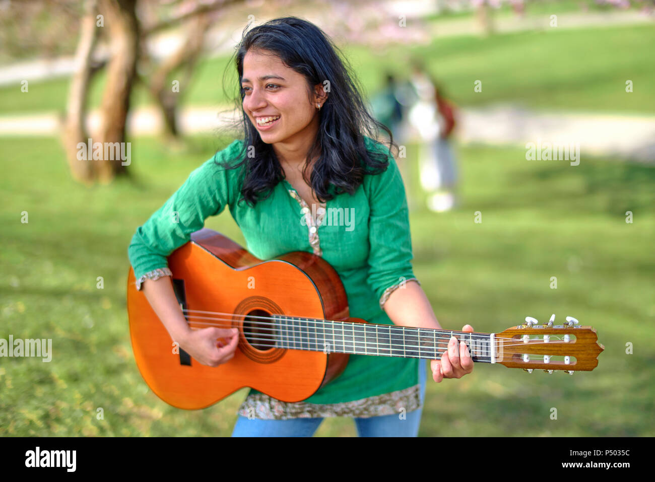 Happy young woman playing guitar in park Stock Photo - Alamy