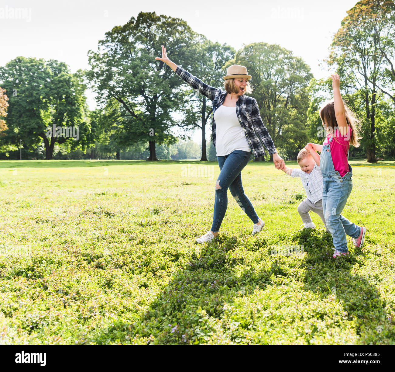 Active happy family walking hand in hand in a park Stock Photo - Alamy