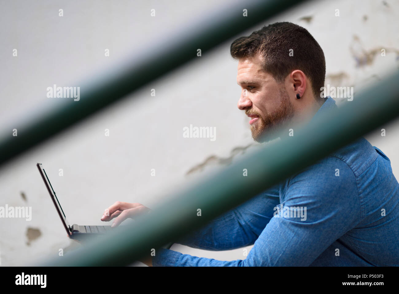 Young man sitting on stairs, working, using laptop Stock Photo