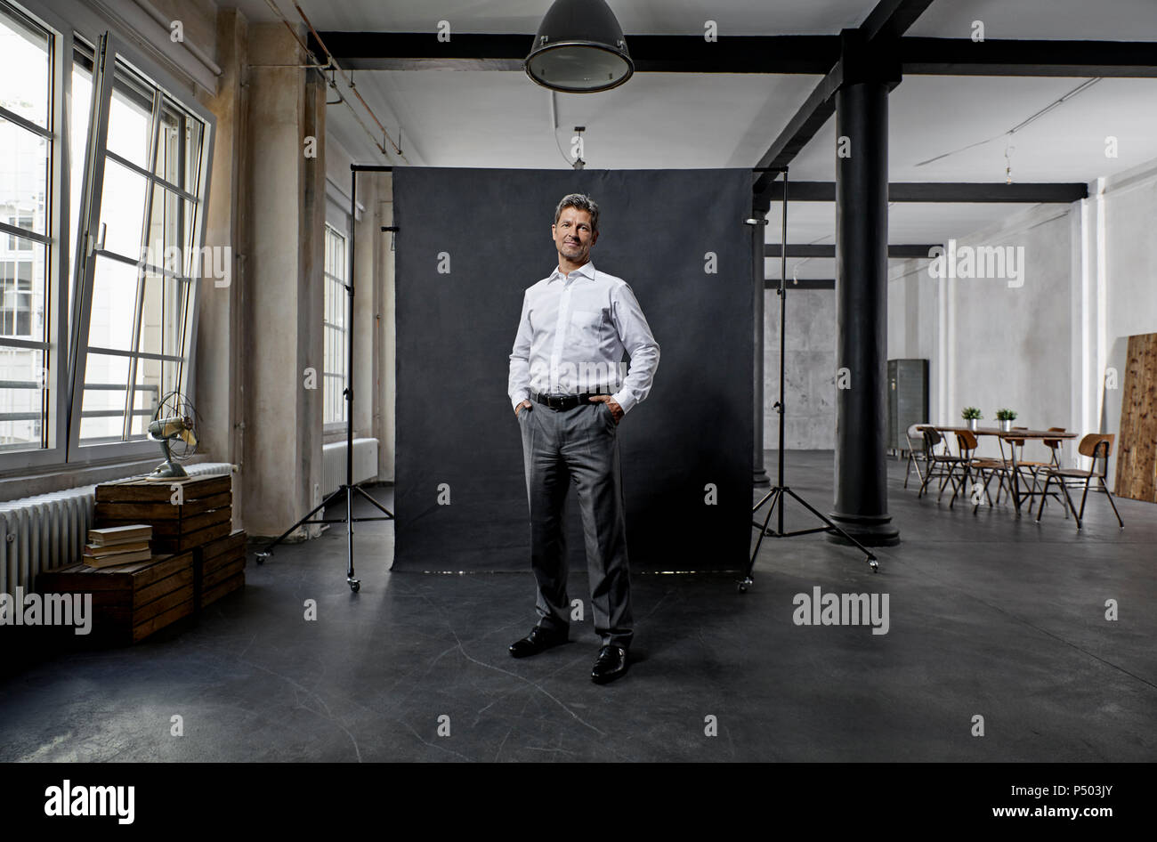 Portrait of mature businessman in front of black backdrop in loft Stock Photo
