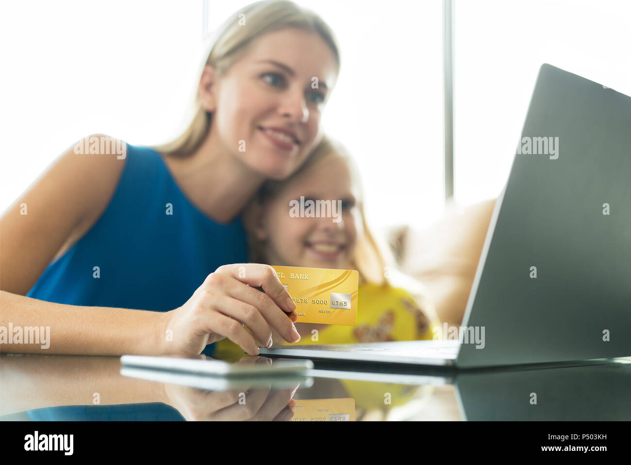 Mother and daughter using laptop and credit card together Stock Photo
