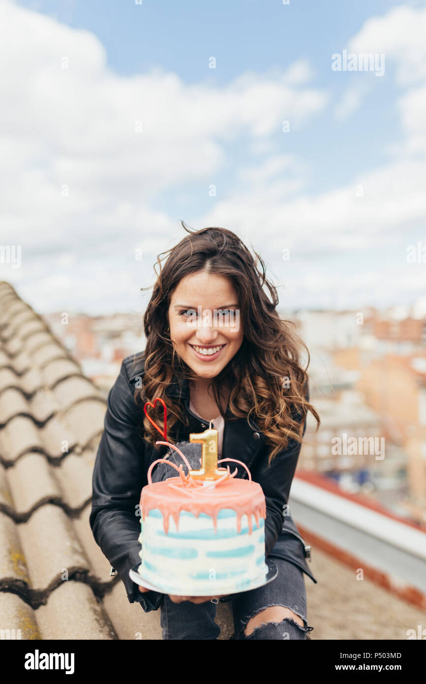 Portrait of woman presenting Birthday cake on roof Stock Photo