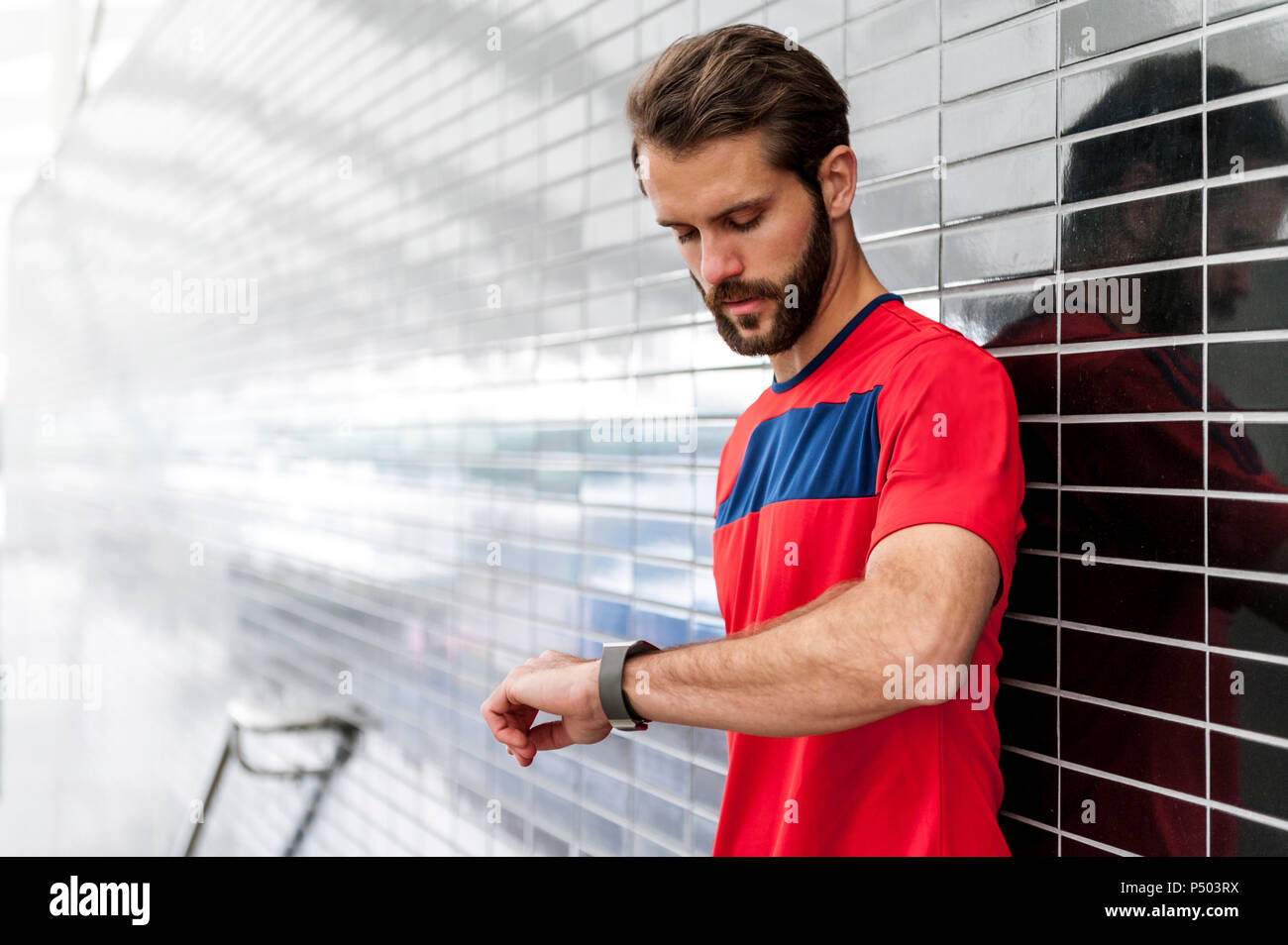 Man having a break from running checking the time on a smartwatch Stock Photo