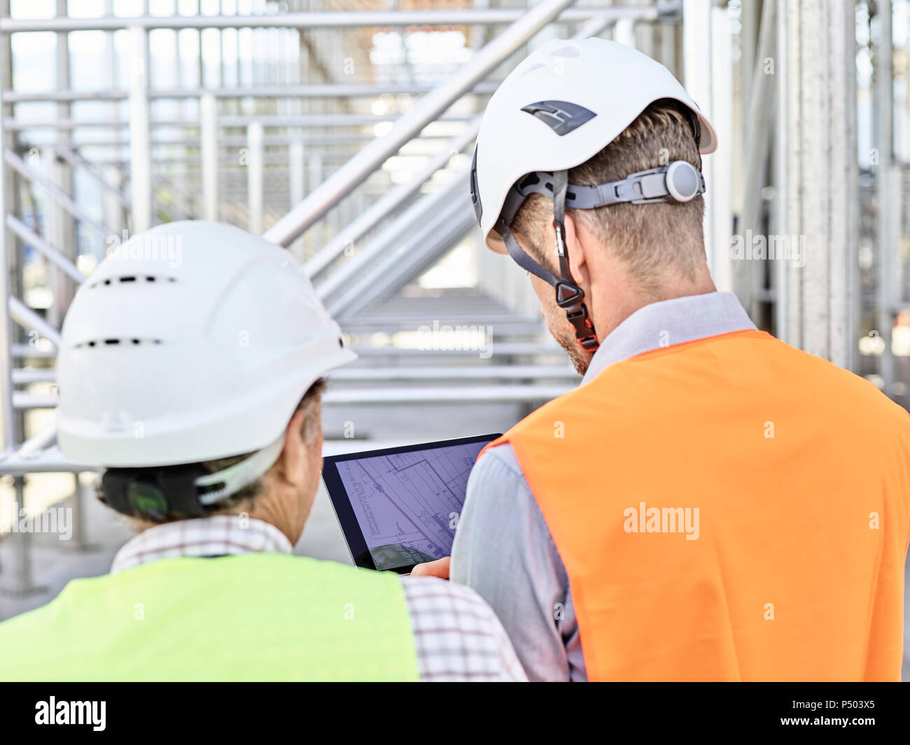 Architect and foreman with tablet wearing hards hat on construction site Stock Photo