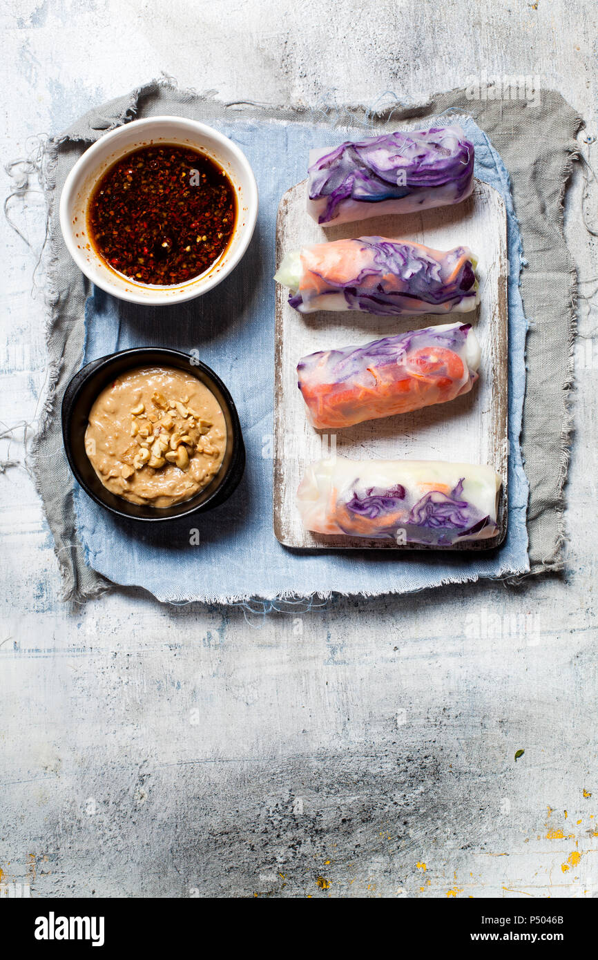 Vegan rice paper wraps (vietnamese summer rolls), filled with cabbage, carrots, bell pepper, rice noodles and dipping sauce Stock Photo
