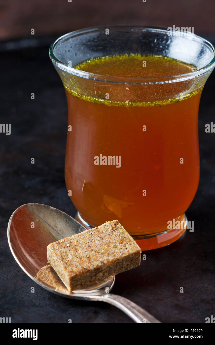 Glass of stock and stock cube on tea spoon Stock Photo