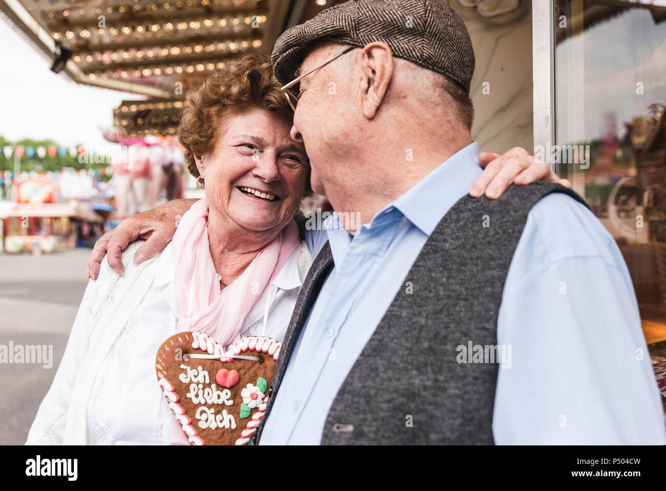 Happy senior couple with gingerbread heart on fair Stock Photo