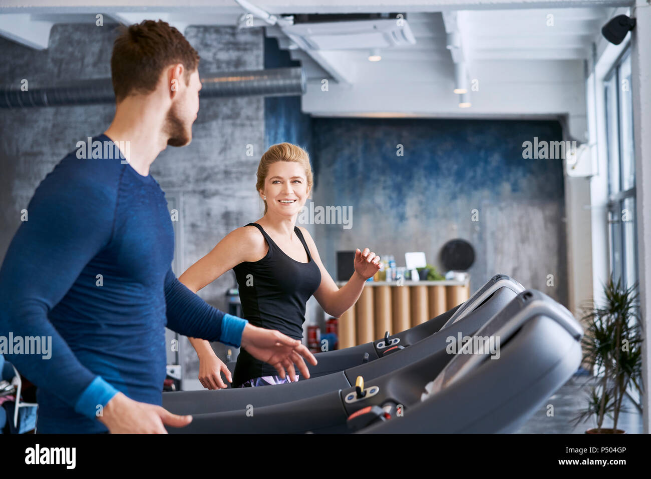 Man and woman talking during treadmill exercise at gym Stock Photo