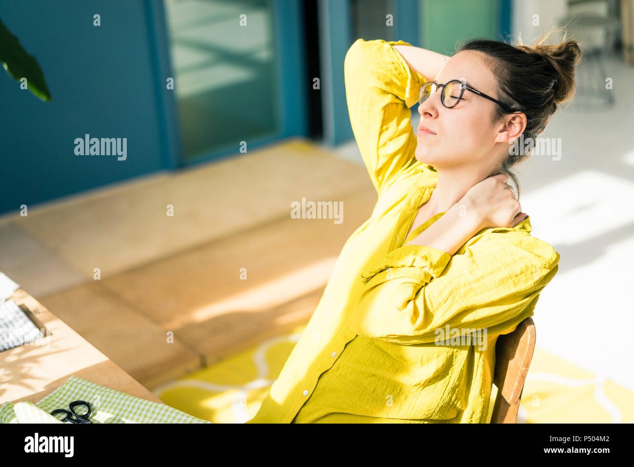 Young fashion designer relaxing at desk in her studio Stock Photo