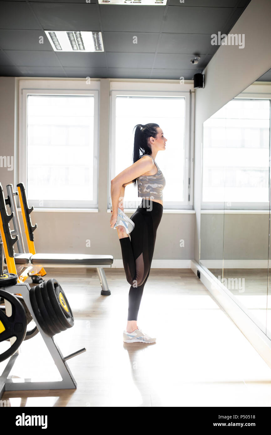 Woman exercising in gym looking in mirror Stock Photo