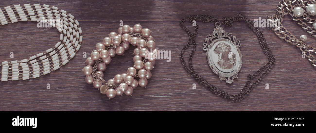 Banner Set of vintage jewelry on a dark wooden background. Necklace pearl cameo locket watch view from the top Flat lay Stock Photo