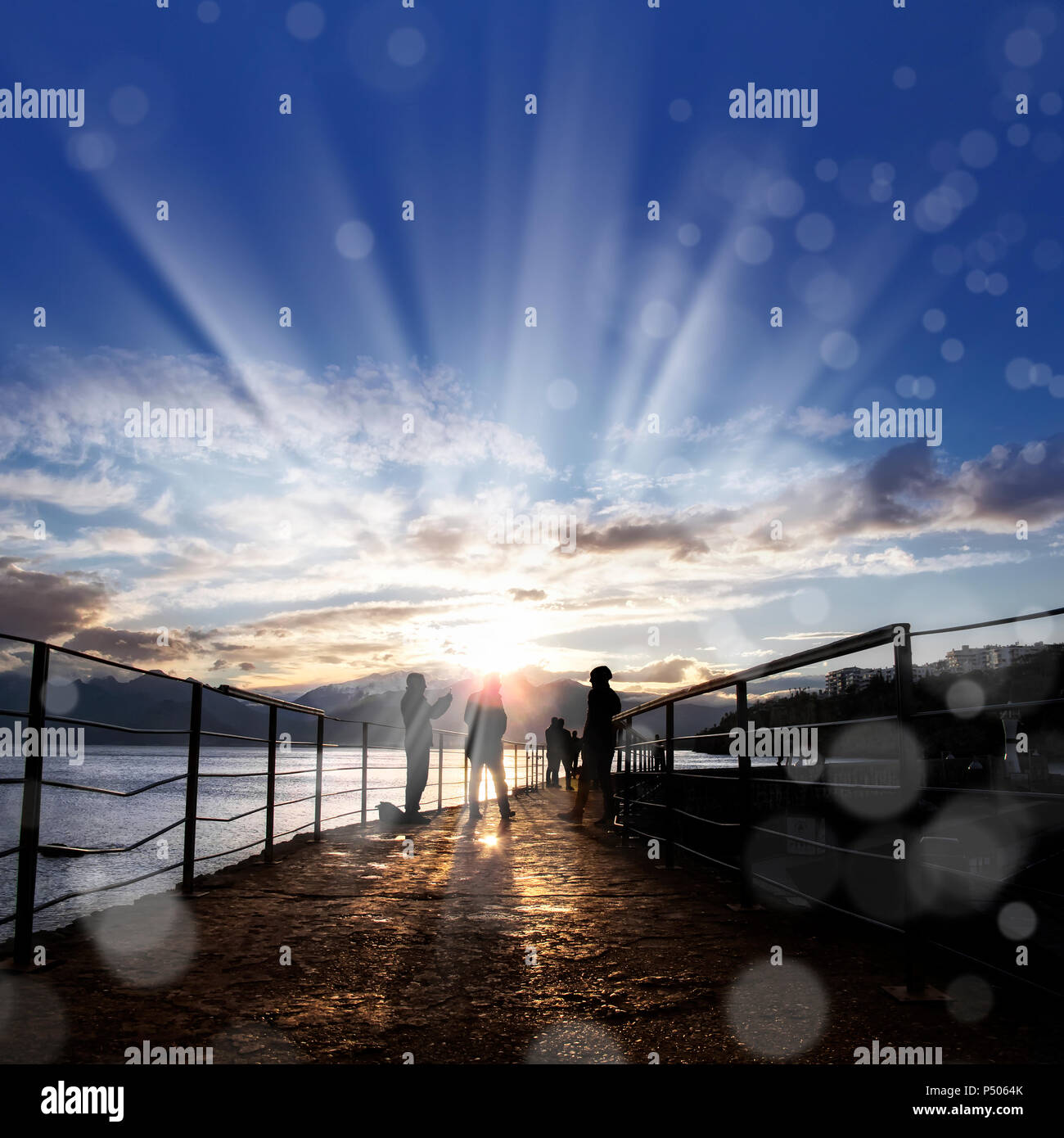 silhouetted people walking on street over sunset sky with sunbeam Stock ...