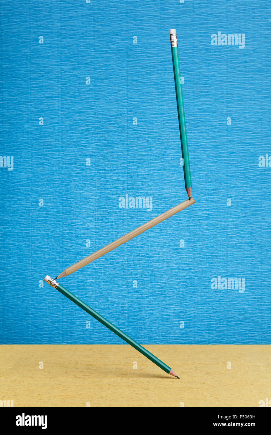 Three lead pencil float in air at weightlessness on blue backdrop. Stock Photo