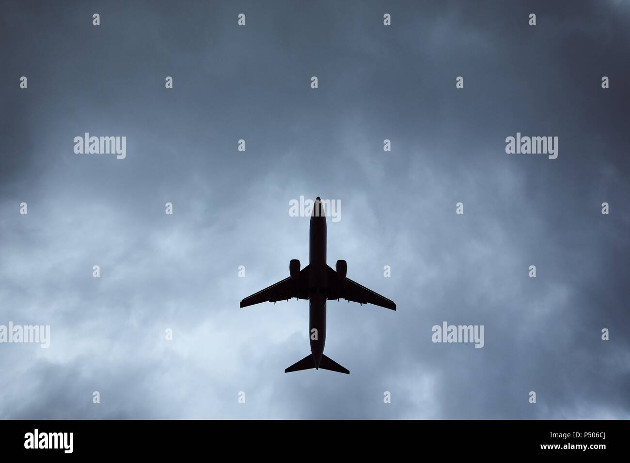 Plane in dramatic cloud. Low angle view of airplane during landing in wind storm. Stock Photo