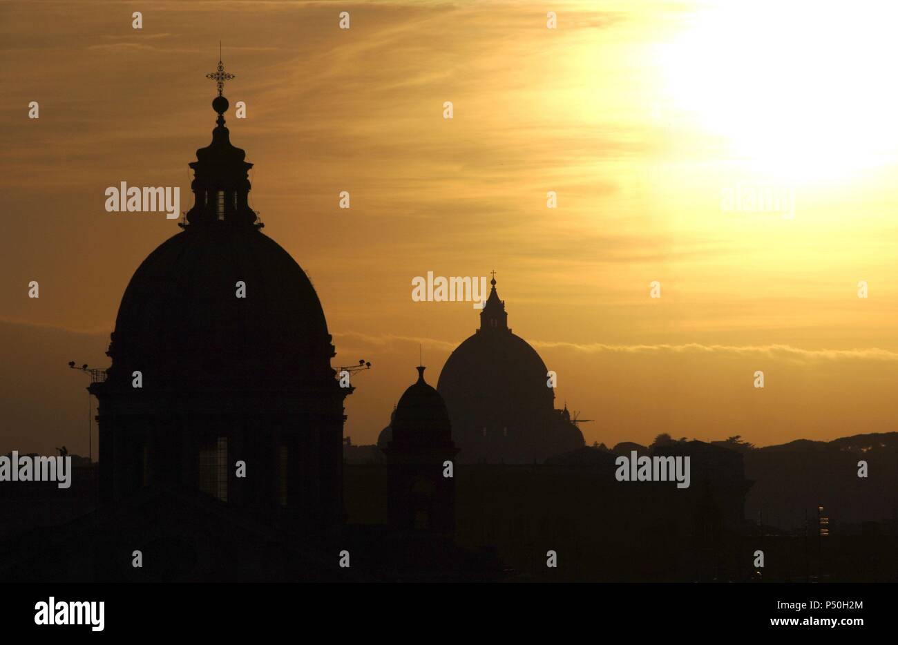 Italy. Rome. Sant'Ambrogio e Carlo al Corso, usually known as San Carlo al Corso with the dome of St. Peter's Basilica in the background, at sunset. Backlighting. Stock Photo