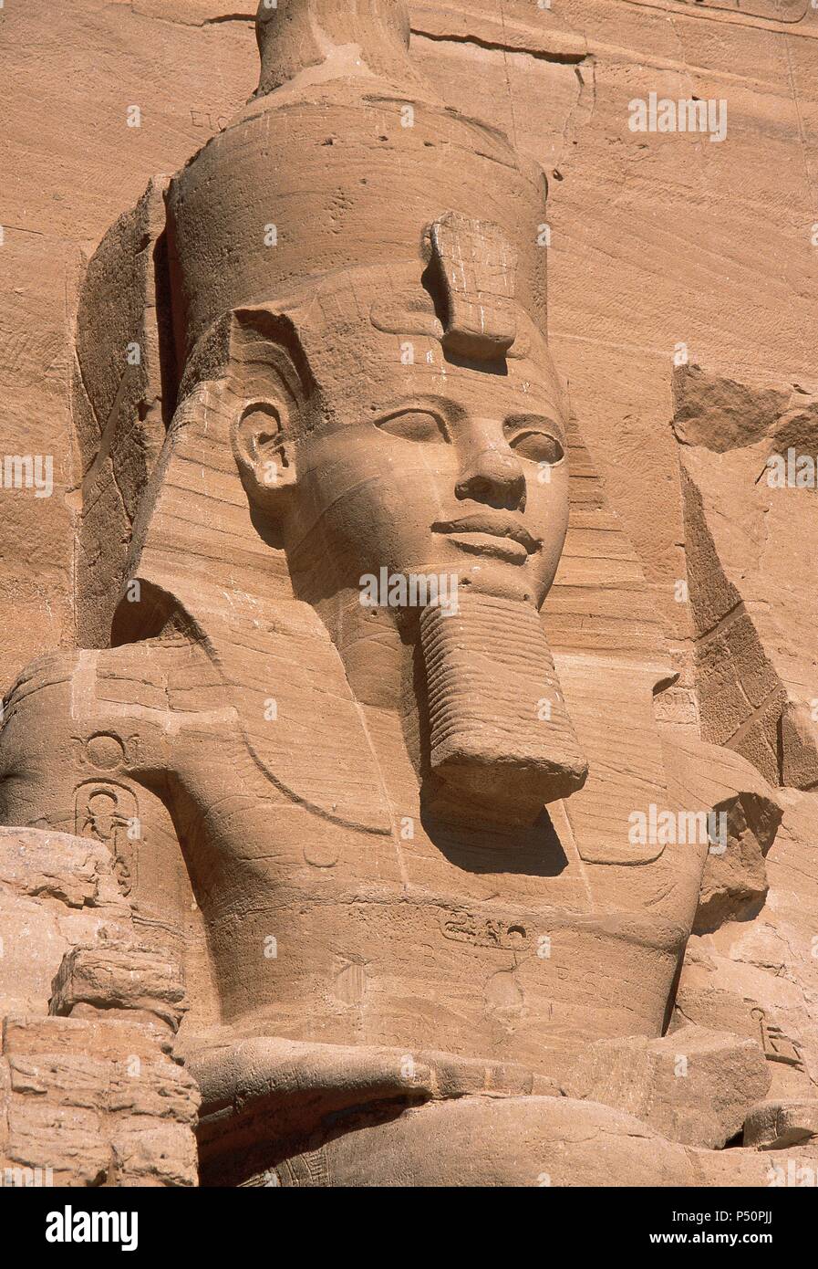 ARTE EGIPCIO. EGIPTO. COLOSO de la fachada del Templo de Ramsés II (templo mayor). Representa al faraón sentado, con el nemes en la cabeza, doble corona, las manos apoyadas en las caderas y rostro sonriente. Abu Simbel. Stock Photo