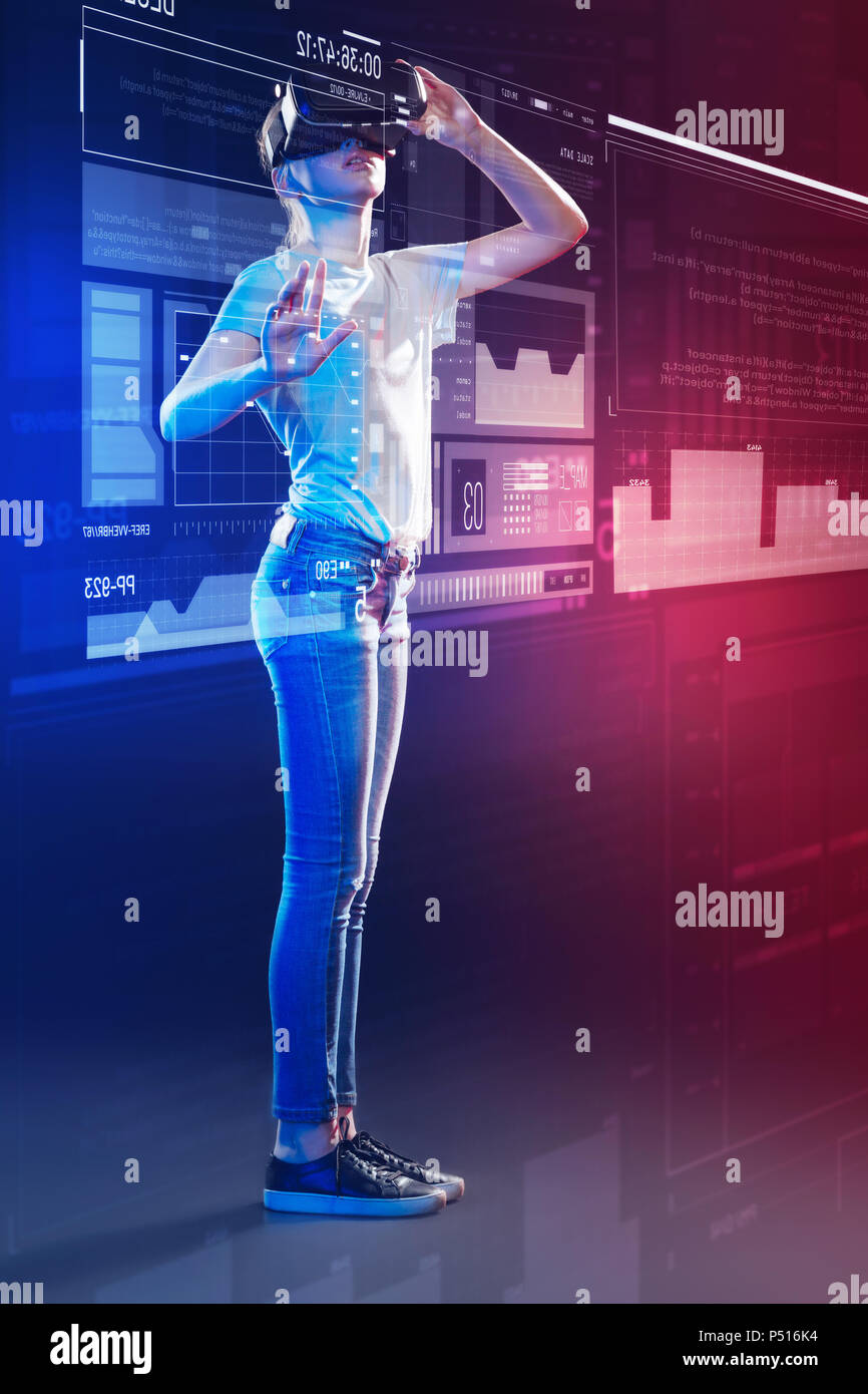 Modern girl standing in front of a hologram and wearing virtual reality