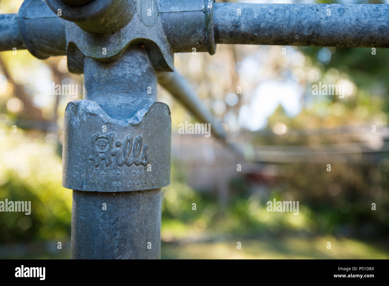A partial view of the centre post and brand name of a 1960's Hills Hoist steel clothes drying line in a backyard in Australia Stock Photo