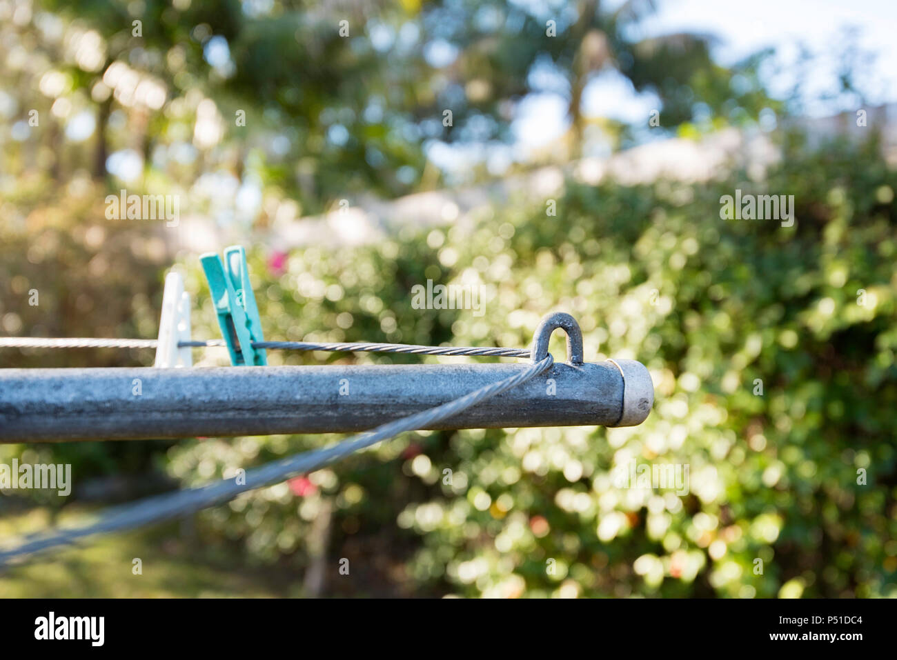 A partial view of the wire line and wing or arm of a 1960s Hills Hoist clothes drying line with clothes pegs in a backyard in Australia Stock Photo