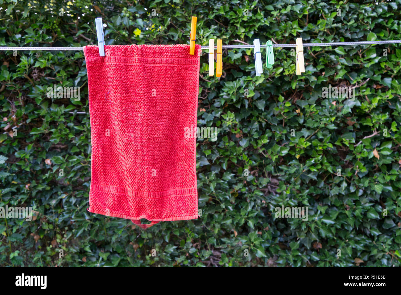 a red towel hanging to dry outdoors in the garden Stock Photo